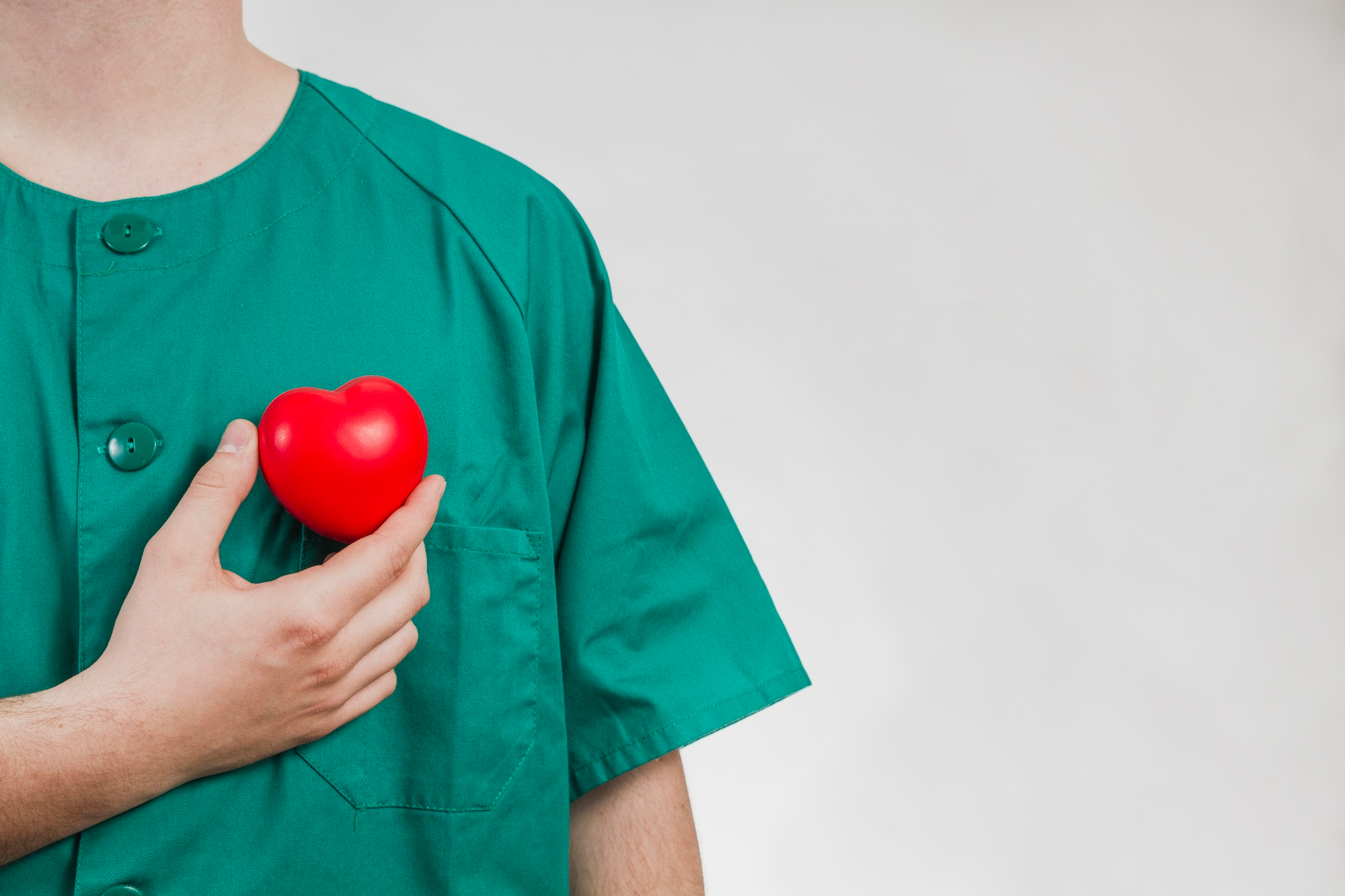 Enfermeiro segurando um coração de plástico simbolizando prevenção de saúde.